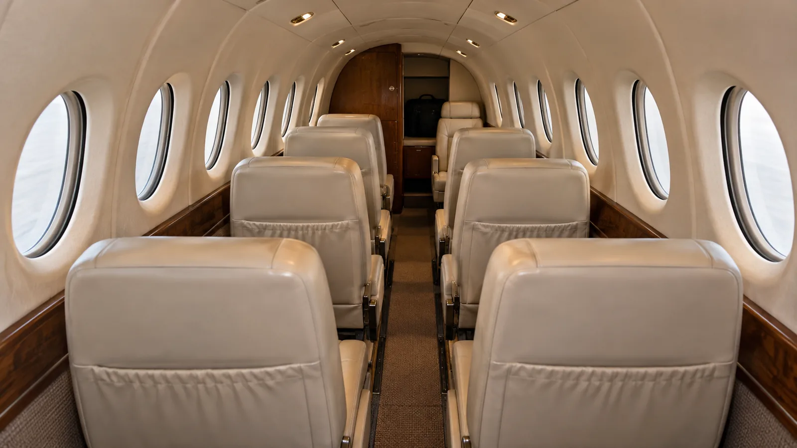 Beechcraft B200 (PT6A-42 design reference) cabin interior illustration: generated illustration of a compact Beechcraft B200 cabin with paired passenger rows and one aft seat.