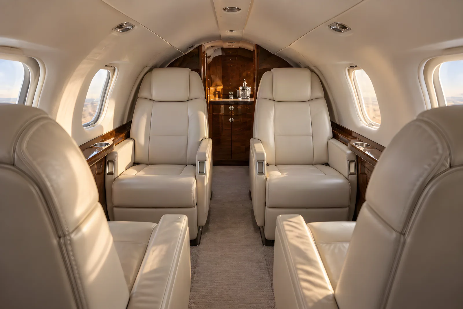 Eclipse 500 cabin interior illustration: warm natural light illuminates three cream leather seats, wood trim and rounded windows in the low, narrow Eclipse 500 cabin viewed aft from seated eye level.