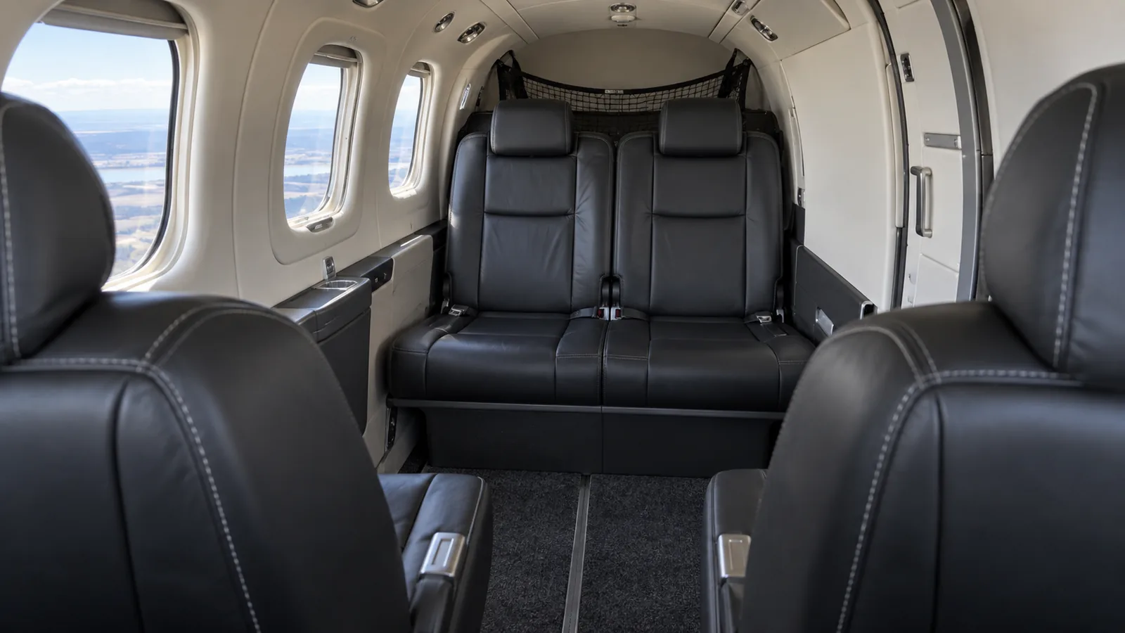 Representative TBM 850 standard cabin looking aft, with two aft-facing middle chairs opposite a two-place forward-facing rear bench